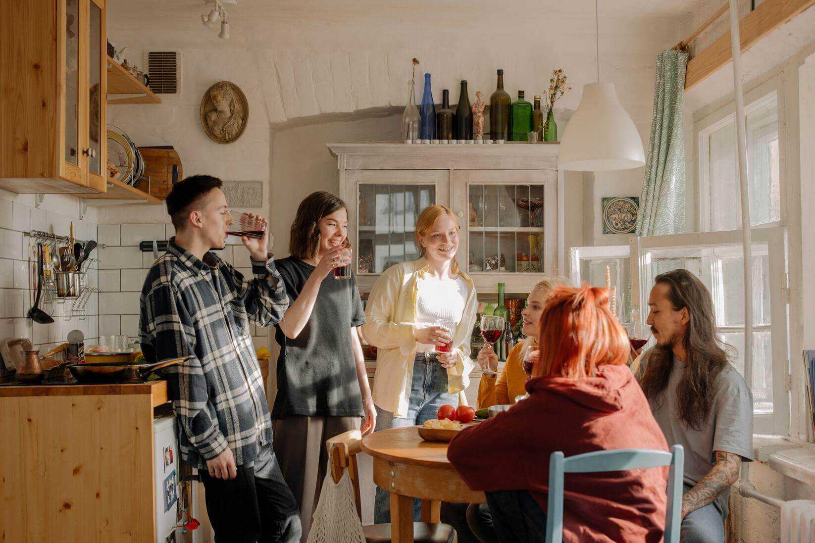 Happy roommates sitting in the kitchen, chatting.